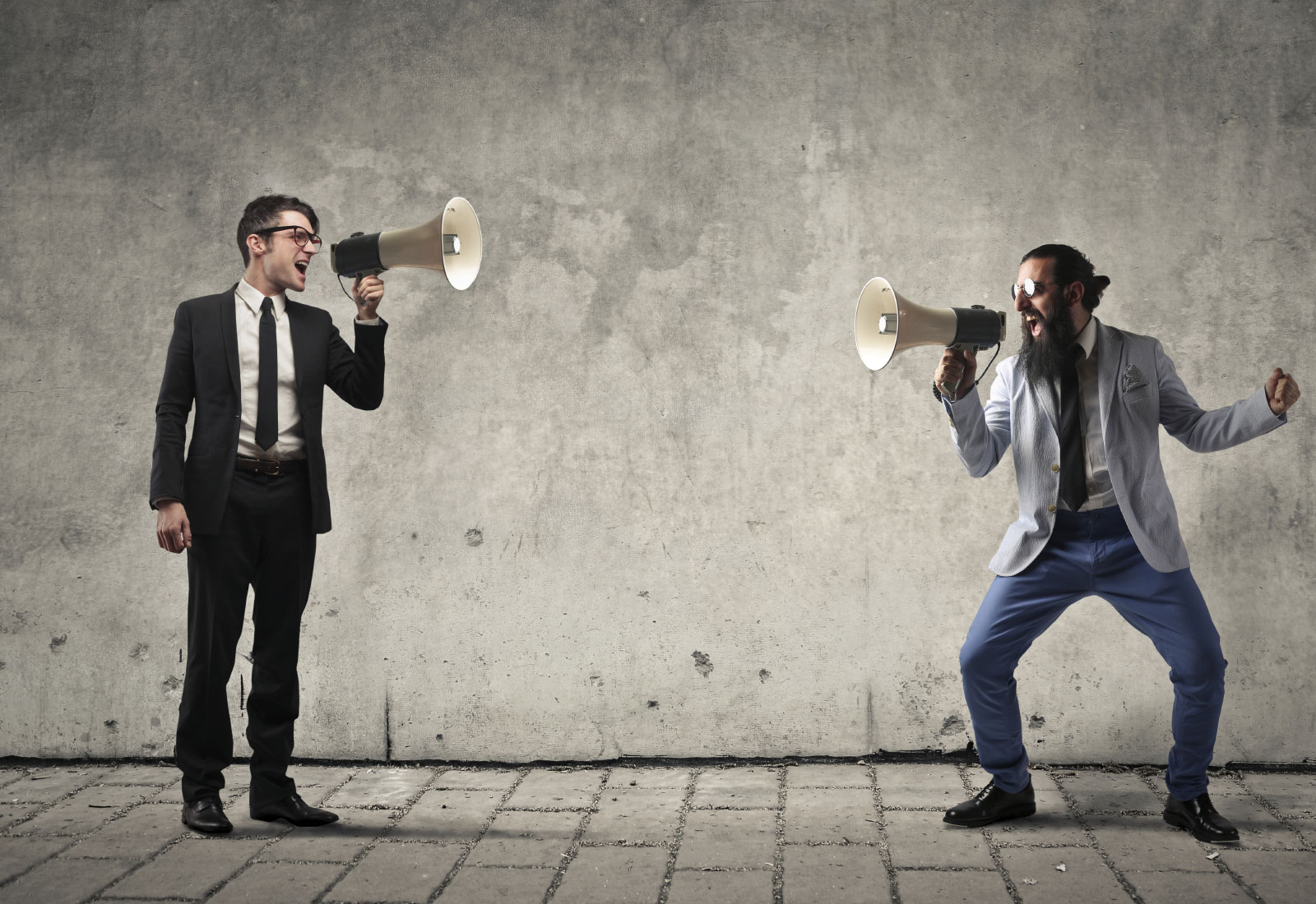 Businessman und Hipster kommunizieren über Megafone | KLÄRUNGSHILFE MÜNCHEN | www.wir-klaeren.de